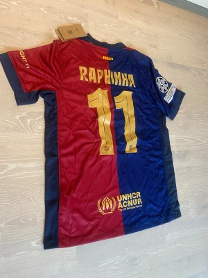 HELT NY FC Barcelona matchtröja Raphinha #11 - •Hej! Säljer en jätte röd blå Barcelona 24/25 fotbolls T-shirt med Raphina på ryggen ⚽️👕 •Den är inte använd bara testad.  •Det är storlek M och den har inga hål eller liknande. •Måtten är på dem sista bilderna 📐.  •Priset kan diskuteras och skickar inom 24 Tim😊💨