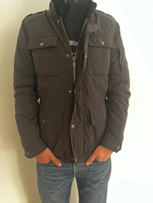 Massimo Dutti Fieldjacket: S - Säljer en superfin fodrad fieldjacket från Massimo Dutti. Jackan är fodrad vilket gör den grym för kyligare dagar🤩. Den är i storlek M men sitter som S. Jackan har även en luva som fälls ut baktill genom kragen. Hör av er vid yttligare frågor☺️(Jackan är brun men ser lite grå ut i bilderna pga dåligt ljus)