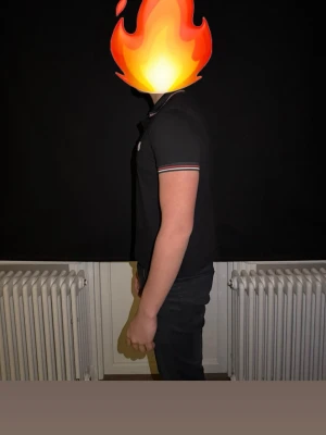 Svart Moncler piké - Säljer en svart pikétröja från Moncler med klassisk krage och korta ärmar. Pikén har tunna ränder i rött och vitt på krage och ärmslut samt Moncler-logga på bröstet. Passformen är normal och materialet känns som bomull. Perfekt till chill och snygga outfits.