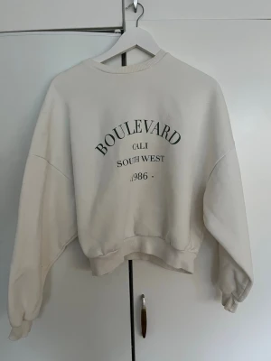 Vit collegetröja med tryck  - Säljer denna vita collegetröjan från Nelly i storlek XS. Den är i mycket bra skick, jag har använt den 2-3 gånger🤍