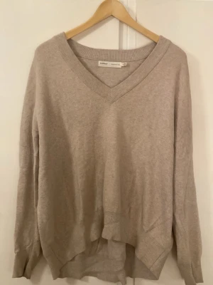 Beige stickad tröja från InWear - Säljer en beige stickad tröja från InWear i storlek M. Tröjan har en bred v-ringad hals och långa ärmar med ribbade muddar. Den är loose fit och har en mjuk och skön känsla, perfekt för lager-på-lager under hösten och vintern.