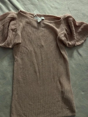 Beige,rosa stickad topp med puffärm  - Säljer en beige stickad topp från Aéryne med puffiga korta ärmar och rund hals. Toppen har ett snyggt ribbat mönster och är gjord i mjukt material som känns skönt mot huden. Perfekt att styla med jeans eller kjol för en cool look.