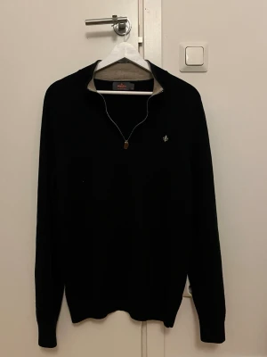 Svart merinoullströja från Morris - Säljer en svart långärmad tröja från Morris i 100% merinoull. Tröjan har en stilren half zip-dragkedja och en liten broderad logga på bröstet. Perfekt till jeans eller chinos för en clean look. Står XXL i nacken men sitter som M se bild 4, hör av dig gällande frågor!