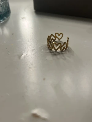 Guldfärgad ring med hjärtmönster - Använt ca 5-7 gngr justerbar inga skador eller sånt! Skriv för fler bilder 💕🫰
