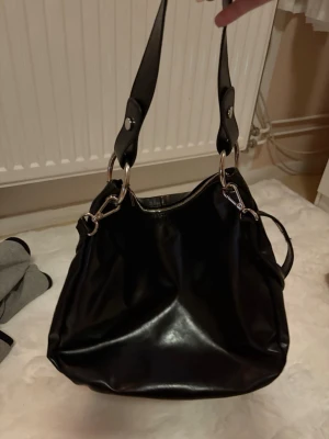 Svart axelväska  - Väldigt fin och bra storlek på en väskan till en vanlig vardag eller till jobbet/skola. Den har en innefika som passar bra att lägga nycklar och plånbok 