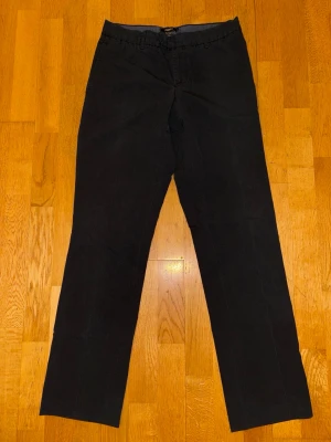 Svarta kostymbyxor från Filippa K - Stilrena svarta kostymbyxor från Filippa K i rak modell. Byxorna är gjorda i en skön mix av bomull, polyester och lite elastan för extra komfort. Perfekta för dig som gillar en klassisk look med modern touch.