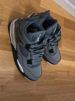 Nike Air Jordan 4 Retro grå/gul - Säljer ett par Nike Air Jordan 4 Retro i grått med svarta och vita detaljer samt gula inslag har använt max 1 gång. Kom gärna dm om ni undrar över något. kan passa på 44 