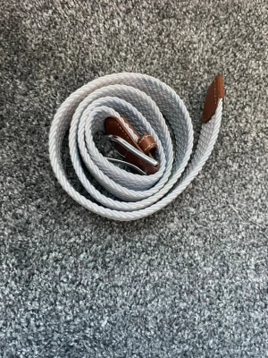 Ett vitt flätat bälte  - Ett vitt flätat bälte som har en simple men klassisk look vilket lyfter upp ens outfit