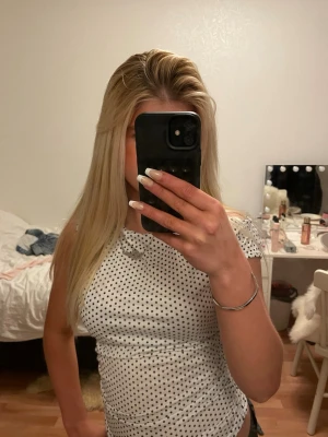 Vit prickig offshoulder topp - Säljer en vit ärmlös topp med svarta prickar och lätt draperad halsringning. Toppen har en tight passform. Storlek XS. Säljer på grund av att den aldrig kommit användning. Aldrig använd!💓