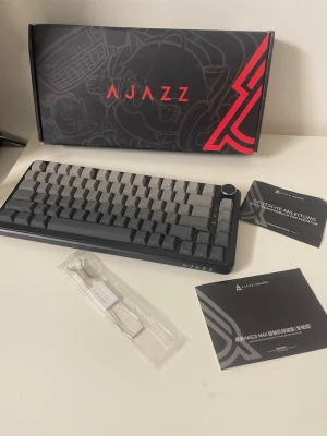 Ajazz AK820 Max Mekaniskt Tangentbord - Ajazz AK820 Max är ett kompakt mekaniskt tangentbord med bakgrundsbelysta tangenter och volymratt. Levereras komplett med originalkartong, manualer och verktyg. Tangentbordet är i mycket gott skick, utan synligt slitage. Perfekt för gaming och produktivitet.