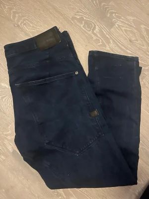 Mörkblå tapered jeans från G-Star Raw - Säljer ett par mörkblå jeans från G-Star Raw, modell TYPE C 3D Loose Tapered. Byxorna har en avslappnad passform med avsmalnande ben och stora bakfickor. Tillverkade i slitstarkt bomullsmaterial och perfekta för en chill och stilren look.
