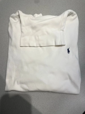 Klassisk Polotröja från Ralph Lauren - Två stilrena pikétröjor från Ralph Lauren, en i vit och en i marinblå. Båda har den ikoniska broderade loggan på bröstet och är tillverkade i mjuk bomull. Perfekta för en clean och tidlös look.