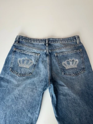 Rhinestone jeans  - Zara straight leg jeans med handgjorda rhinestone-kronor på bakfickorna 👑✨Tvättas ut och in på låg temperatur! Låg till medelhög midja, Y2K-inspirerade. Unikt custom-plagg, finns bara ett. Väldigt fint skick. Midja:41cm, Innerbenslängd: 80cm