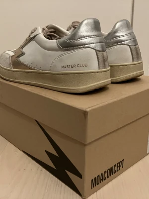 MOA Concept Master Club sneakers 39 i toppskick  - Superfina och eftertraktade sneakers i läder med skimrande detaljer. Modell Master Club MG585. Vita (Färg: ”Pink gold laminated m logo white”) Parti i mocka fram. Uttagbar, skinnklädd innersula. Köpt på Ellos sommaren 2025 för 2495,-. 