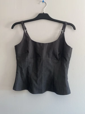 Mörkgrå linnetopp från hm  - Säljer en stilren mörkgrå linnetopp från hm PASSAR STORLEK S OCKSÅ med justerbara smala axelband. Toppen har en lätt figurnära passform och är sydd i ett slätt, mjukt material som ger en clean look. Perfekt att matcha med jeans eller kj soppa. Liten i storleken!!!!!!aldrig använd 