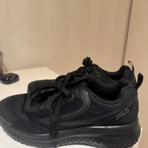 Svarta Fila sneakers med snörning - Svarta fila skor, perfekt till gym, jobb eller till vardags. Dessa skor är iprincip helt nya, används 1 gång till jobb men behövdes ej mer där efter. 