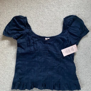 Blekblå topp - Mörkblå topp från Nelly med puff ärmar. Säljer denna då jag glömde lämna tillbaka den. Den är helt oanvänd med prislappen kvar. 
