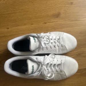 Adidas Stan Smith vita sneakers - Adidas Stan Smith sneakers i vitt skinn med gröna detaljer. Klassisk låg modell med snörning. Finns vissa märken men inte så farligt. Ser nästan oanvända ut. 