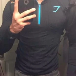 David Laid Onyx Inspirerad Compression Shirt - Säljer en svart compression shirt med onyx inspirerad mönster och färg, i storlek S. Tröjan har en halv dragkedja framtill i blått och matchande blått foder i huvan. Perfekt för träning och gym, långärmad och i mjukt material.