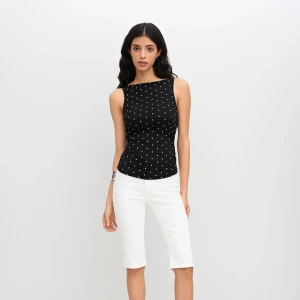 Svart prickig linnetopp med knyt - Svart ärmlös linnetopp med vita prickar och rund halsringning. Toppen har öppen rygg med snygg knyt-detalj bak som ger en cool twist. Figurnära passform och mjukt, lätt material – perfekt för varma dagar.