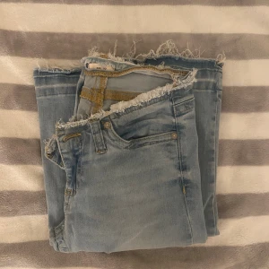 Ljusblå jeans med råa kanter från Nelly - Snygga ljusblå jeans från Nelly med råa, fransiga kanter både vid midjan och bensluten. Klassisk femficksmodell med slitna detaljer och kontrastsömmar. Perfekt för dig som gillar en avslappnad och trendig look.