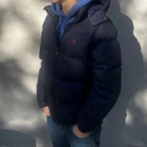 Ralph Lauren jacka marinblå - En fin och varm jacka för vintern. Bra skick, endast använd 1 vinter. Säljer pågrund av att den blivit för liten. 