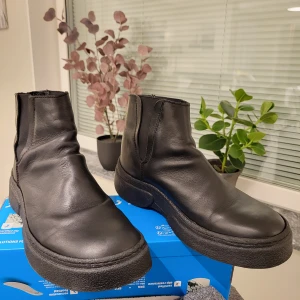 Svarta chelsea boots från Björn Borg 42 passar 43 - Stilrena svarta chelsea boots från Björn Borg i skinn med elastiska paneler på sidorna och grov, räfflad sula. Klassisk rund tå och platt sula gör dem både snygga och bekväma. Perfekta för dig som gillar minimalistisk och tidlös stil.