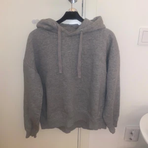 Grå hoodie från 157 med huva - Mjuk och chill grå hoodie från 157 i storlek M. Tröjan har huva med snörning och långärmade muddar. Insidan är fleecefodrad för extra komfort och värme. Perfekt för kalla dagar och när du vill vara extra cozy.