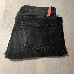 Svarta jeans från Acne Studios Blå Konst - Snygga svarta jeans från Acne Studios Blå Konst med klassisk femficksdesign och rak passform. Jeansen har en cool svart tvätt och detaljerad etikett i midjan. Perfekta för dig som gillar stilrena och trendiga jeans med svensk design.