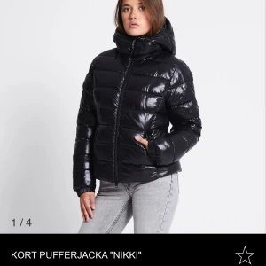 Svart kort pufferjacka Nikki - Säljer en svart, glansig och kort pufferjacka från Lager157  med huva och dragkedja framtill. Har använts ett fåtal gånger och är köpt för 400kr. Fråga gärna om ni har funderingar. 