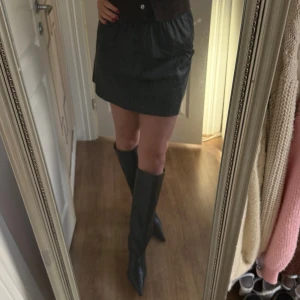 Svart kort kjol i skinnimitation från ONLY - Säljer en svart kort kjol från ONLY i skinnimitation med elastisk midja. 