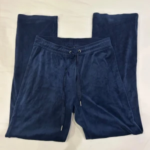 Mörkblå mjukisbyxor med snörning - Säljer ett par mörkblå mjukisbyxor med breda ben och snörning i midjan. Byxorna är tillverkade i ett mjukt och lent material som känns skönt mot huden. Perfekta för chill dagar eller när du vill vara extra bekväm. Stilen är loose och passformen är relaxed.