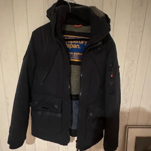 Superdry vinterjacka  - Detta är en jacka för dig som inte vill frysa i vinter, det är dubbelt lager på jackan. Den är i jätte fint skick finns dock en lagning på armen. Storlek L passar mig som är 182 och väger 72. Passar dock längre personer.