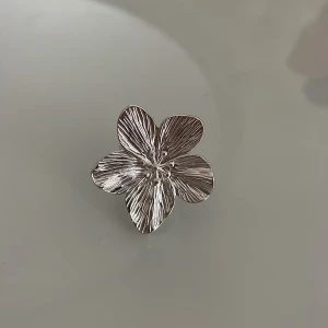 Stor silverring med blomform - Statementring i silverfärgad metall formad som en stor blomma med fem detaljerade kronblad. Ringen har en snygg, glansig finish och tydliga ådringar på blommans blad som ger en cool och unik look.