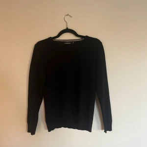 Svart stickad tröja från J.Lindeberg - Svart stickad tröja från J.Lindeberg i storlek S. Obs: den har Tyvär blivit tvättad och krympt lite grann, skulle säga att den passar mer åt xs hållet. Sitter nog bäst om du är mellan     165cm -170cm. Den är riktigt skön och passar till nästan allt. Hör av dig om du har några frågor.🤗
