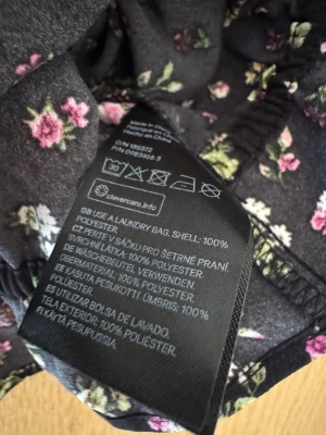 Blommig rosett volangtopp - Blommig topp med volanger och rosetter. Storlek XS-S. Svar, rosa, grön.