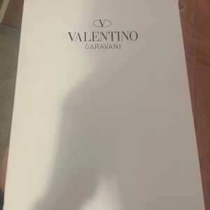 Valentino Garavani Open Sneakers vit/blå - Säljer ett par Valentino Garavani Open Sneakers i storlek 43. Skorna är vita med en bred mörkblå rem över mitten och har snörning framtill. Tillverkade i mjukt kalvskinn för en lyxig känsla och har en platt sula. Perfekt för dig som vill ha en clean och stilren look.