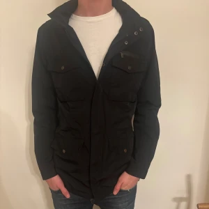 Fieldjacka Riley - Skitsnygg fieldjacka från märket Riley i storleken 48 vilket motsvarar M. Jackan är i mycket bra skick utan defekter. Hör av er vid eventuella frågor!