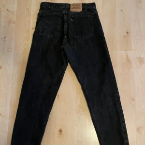 Svarta Levi's 550 jeans W31 L30 - Svarta Levi's 550 jeans med relaxed fit och avsmalnande ben. Klassisk femficksmodell med knapp och dragkedja fram. Tillverkade i 100% bomull.