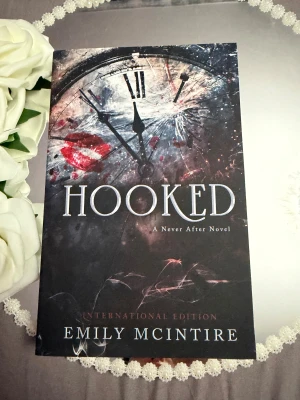 Hooked - En mörk och spännande roman ur serien 'A Never After Novel'. Perfekt för dig som gillar intensiva berättelser med mystik och oväntade vändningar. Omslaget lockar med krossad klocka och röda läppavtryck – en bok som sticker ut i bokhyllan!
