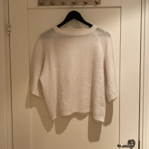 Vit stickad kortärmad tröja från 157 XS - Mysig vit stickad tröja från 157 i storlek XS. Tröjan har rund hals och trekvartsärm, perfekt för lager-på-lager under höst och vinter. Enkel och clean design som funkar till jeans eller kjol. Ribbad kant vid hals och nederdel.