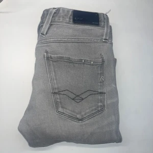 Replay Anbass jeans - Replay Anbass jeans i ljusgrå tvätt med klassisk femficksdesign och svarta sömmar på bakfickorna. Slim fit-modell med smal passform och normal midja. Tillverkade i mjukt jeanstyg som sitter skönt hela dagen. Midja 36cm, längd 96cm.  Ifall det inte finns någon bild i annonsen där jag bär plaggen jag säljer så är det för att jag ej kan ha storleken heller passformen, så kolla måtten för storlek och googla på modellnamnet för passform 😉 40