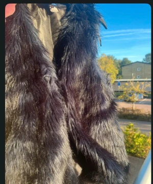 Svart fluffig pälsväst - Säljer en svart pälsväst med lång, glansig och fluffig päls. Västen har en öppen front och är perfekt för att ge din outfit extra edge. Materialet är mjukt och ger en lyxig känsla. Passar dig som vill sticka ut och gillar statement-plagg. Använd 1 gång