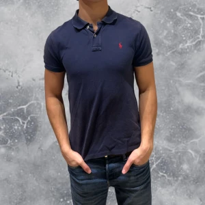 Ralph Lauren Piké Navy Blå - •Ralph Lauren Piké Navy Blå Skick: 7/10, Inga skador (lite solblekt). Storlek: 14/16 år~160-170 cm. Modell: 174 cm, 63 kg. Authentic: ✅. Hör av dig vid frågor eller funderingar, mvh Hessler’s;)