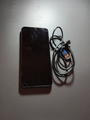 Ulefone AI Cam Smartphone - Ulefone smartphone med AI Cam, säljs med laddningskabel. Skärmen har synliga repor och fingeravtryck, men telefonen ser i övrigt ut att vara i gott skick. Perfekt för dig som söker en prisvärd Android-telefon med grundläggande funktioner.