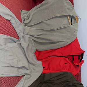 199kr per tröja|  Tre tröjor: röd hoodie, grå kofta, khaki hoodie  - BARA GÖTEBORG!!!! Säljer tre tröjor: en röd hoodie med dragkedja och svarta detaljer, en ribbad ljusgrå kofta med knappar och en khakigrön hoodie med dragkedja och huva. Perfekt för dig som gillar bekväma och stilrena plagg i neutrala färger.