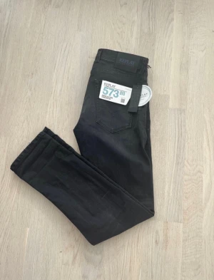 Replay Grover svarta jeans straight fit - Svarta jeans från Replay, modell Grover 573 Bio, med straight fit och klassisk femficksdesign. Jeansen har en mörk tvätt och subtila slitningar för en cool look. Materialet är jeans och passformen är normal, perfekt för dig som gillar stilrena och tidlösa byxor.
