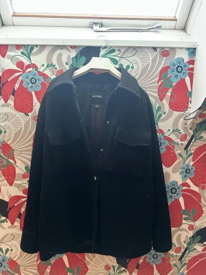 Svart overshirt jacka från Monki - Svart overshirt jacka från Monki i storlek S. Jackan har två stora bröstfickor, klassisk krage och knappar framtill. Materialet är grovt och känns lite ulligt, perfekt för lager-på-lager. 