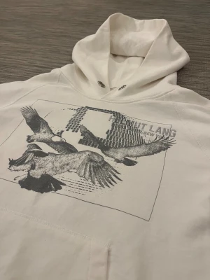 Intressekoll - Helmut Lang Hoodie - Intressekoll för en stilren Hoodie från Helmut Lang. Hoodien är sparsamt använd och har inga skador. Lägg märke till att det finns en liten fläck på innersidan av huvan (syns inte vid användning/se sista bilden) och att snöret har saknas (har ett utbytessnöre som kan skickas med). Utöver detta har tröjan en riktigt fin design som passar till många olika outfits.  Nypris på cirka 5000 SEK!  Storlek M (180+)  Hör av er vid frågor och funderingar och tveka inte över att skicka prisförslag!