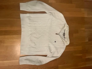 Vit stickad tröja med half zip Morris - Snygg vit stickad tröja från Morris i storlek L men passar i M! Tröjan har ett klassiskt kabelstickat mönster, ribbade muddar och krage med half zip-dragkedja. Liten broderad logga på bröstet och långärmad modell. Perfekt för dig som gillar stilrena och tidlösa plagg. Pris kan diskuteras vid snabb affär